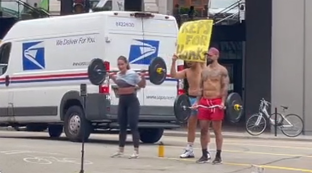 Three people in Goverment Center offering to lift weights for every honk